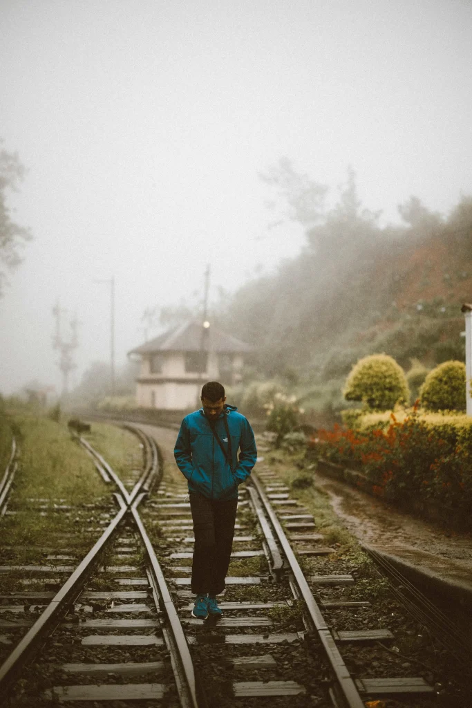man walks through rail road in rainy sri lanka weather